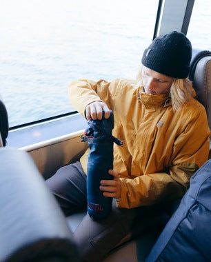 Person in a yellow jacket, opening a Travel Blanket on a boat.