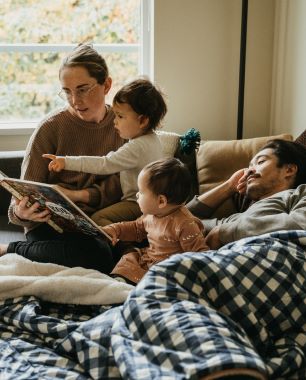 A family reading on a couch with a comfy blanket